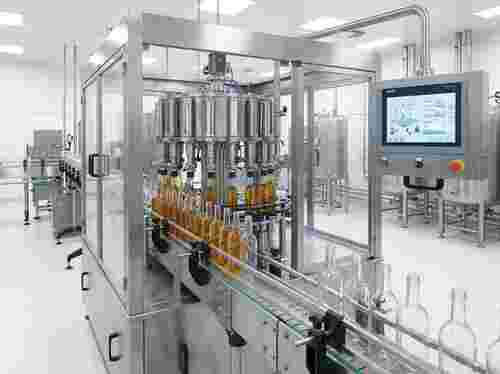 Edelstahl-Füllmaschine in industrieller Abfülllinie mit Flaschen, Förderbändern, digitalem Bedienfeld.